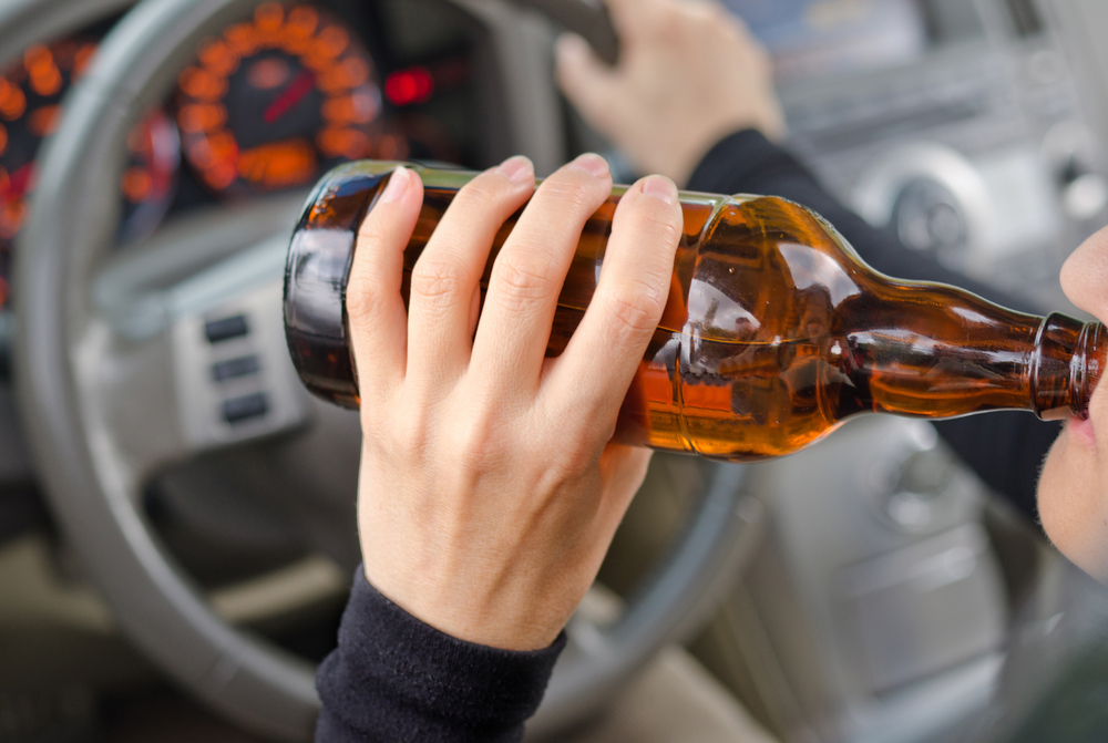 Close up portrait of person drinking alcohol while driving
